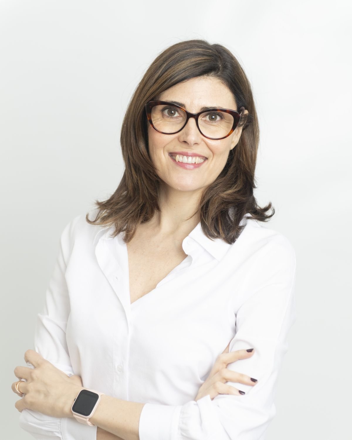 Gemma Mateos sonriendo con los brazos cruzados y camisa blanca